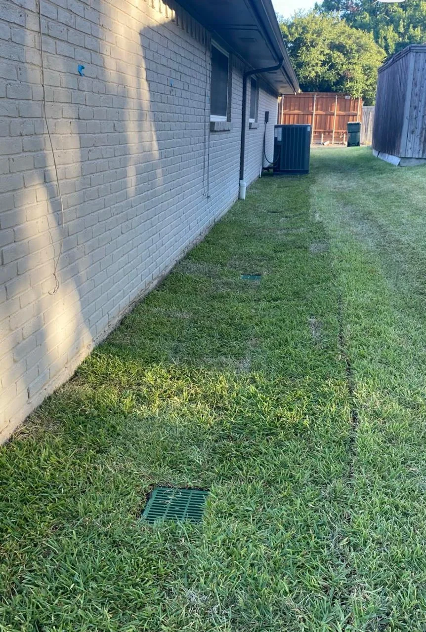 Two catch basins set into a restored residential lawn beside a house