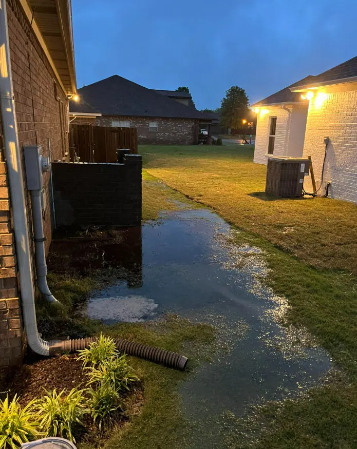 A downspout releasing roof water into a flooded side yard