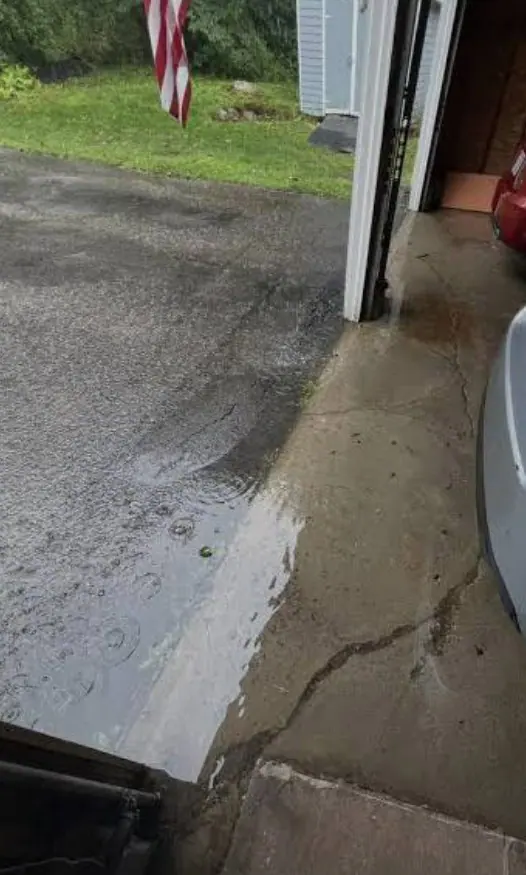 Rainwater pooled along the edge of a residential concrete patio