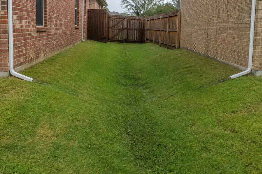 A low grassy corridor between two brick homes where runoff can collect