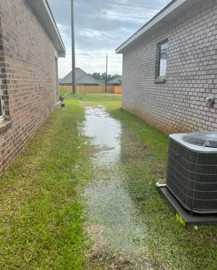 A narrow residential side yard that remains covered with water