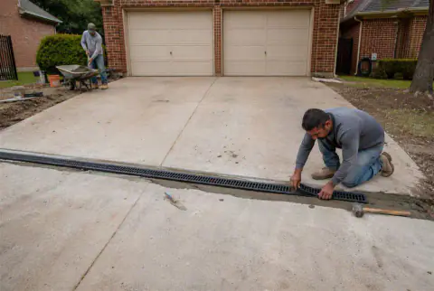 Metal grate installed over a linear channel drain across a concrete surface